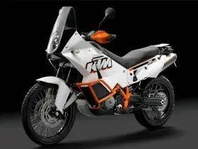 Biały motocykl KTM 990 Adventure z pomarańczowymi akcentami, gotowy na każdą przygodę.