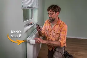 Mann installiert smarten Thermostat am Heizkörper, um Heizkosten zu sparen. "Mach's smart!