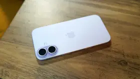 A light purple iPhone with a dual-camera system lies on a wooden surface.