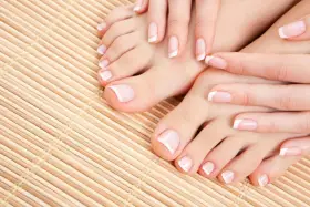 Zadbany pedicure french na stopach i dłoniach, prezentujący klasyczną elegancję na bambusowym tle.