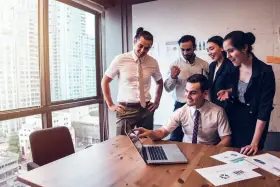 Zespół świętuje sukces. Mężczyzna, który jest business development managerem, wskazuje na ekran laptopa.