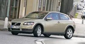 Złoty Volvo C30 z polskimi tablicami rejestracyjnymi WN 70829 jedzie po miejskiej ulicy.