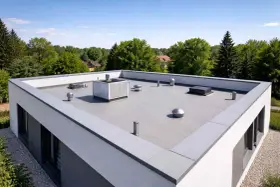 Nowoczesny dach płaski bez attyki z systemem wentylacji i klimatyzacji, otoczony zielenią.