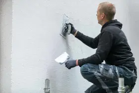 Pracownik nakłada tynk na ścianę, tworząc fakturę. Sprawdź, jaka jest aktualna struktura elewacyjna cena.