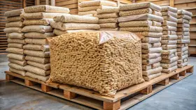 Une palette de bois supporte un grand sac transparent rempli de granulés de bois, entouré de piles de sacs plus petits. Combien de sac de granulés sur une palette ?