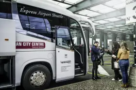 Autobus Express Airport Shuttle z napisem "AN CITY CENTRE Central Station" czeka na pasażerów. Podróż z Mediolan Malpensa do centrum jest prosta.