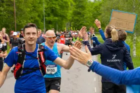 Glada löpare ger high-fives under loppet. Sista veckan innan halvmarathon, peppas deltagarna av publiken.