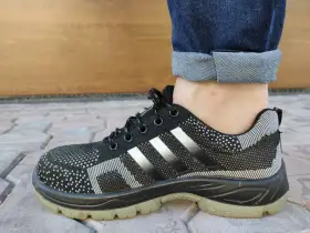 Czarne buty sportowe z białymi paskami i podwiniętymi nogawkami jeansów. Idealny przykład, jak podwinąć spodnie.