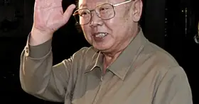 Kim Jong Il w okularach, machający ręką.