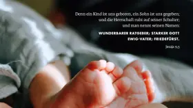 Zarte Füße eines Neugeborenen, umgeben von weichen Stoffen. Der Text zitiert Jesaja 9,5: "Wunderbarer Ratgeber, starker Gott, Ewig-Vater, Friedefürst.
