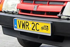 Czerwony grill z logo, reflektor i żółta tablica rejestracyjna z napisem VWR 2C oraz symbolem starego samochodu. To jest rejestracja dw.