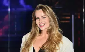 Uśmiechnięta Żaneta Rosińska, której wiek dodaje jej uroku, w białej marynarce i czarnej kreacji.