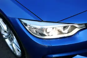 Blå BMW-strålkastare, redo för en prewash. Fälgen syns till vänster.