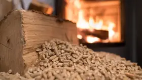 Leña y pellets junto a una estufa encendida. Precaución con los peligros de las estufas de pellets y el almacenamiento seguro.