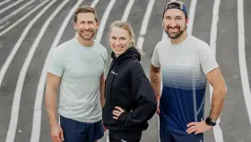 Tre glada löpare på en bana, redo för en bra tid på maraton.