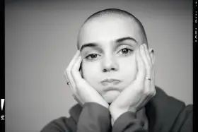 Sinead O'Connor z dłońmi opartymi o policzki, zamyślona.