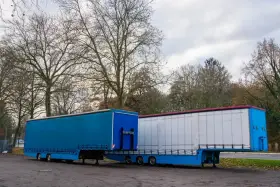 Dwa naczepy ciężarowe, jedna niebieska, druga biała, stoją obok siebie. Symbolizują one dynamiczną branżę TSL.