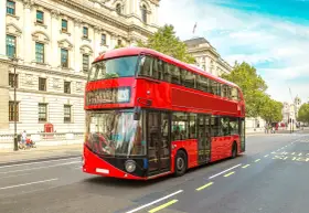 Ikoniczny czerwony autobus piętrowy na ulicy w Londynie, symbol komunikacji miejskiej.