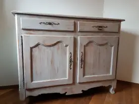 Buffet ancien patiné, avec deux tiroirs et deux portes ornées de poignées en bronze. Le bois présente une finition usée pour un style vintage.