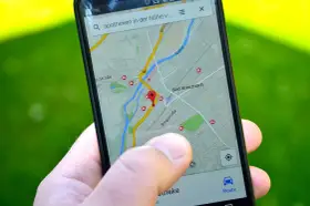 Palec wskazuje na mapę GPS w telefonie, szukając apteki w pobliżu. W samochodzie taka nawigacja to podstawa.