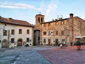 Piazza di un borgo toscano, ideale tra i borghi da visitare in 2 giorni. Edifici in pietra e mattoni, campanile e scorci suggestivi.