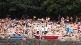 Tłum ludzi odpoczywa na plaży nad jeziorem w Jelczu Laskowicach. Słońce, piasek i woda tworzą idealne warunki do letniego relaksu.