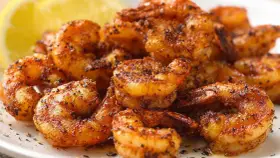 Pyszne krewetki z airfryer, przyprawione i lekko przypieczone, z plasterkiem cytryny w tle.
