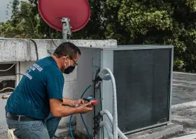 Technik sprawdza czujnik ciśnienia klimatyzacji na dachu, używając manometru.