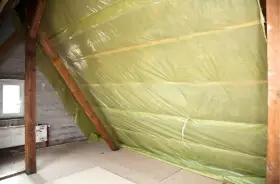 Na poddaszu rozłożona folia paroizolacyjna na drewnianych belkach, chroniąca przed wilgocią.