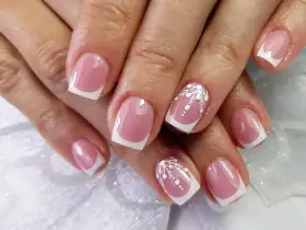 Eleganckie paznokcie żelowe w stylu francuskim z białymi, zimowymi zdobieniami. Idealne, by dowiedzieć się, jak zrobić paznokcie żelowe.