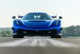 Niebieski Koenigsegg Jesko Attack z agresywnym przednim splitterem i spojlerami, gotowy do ataku na torze.