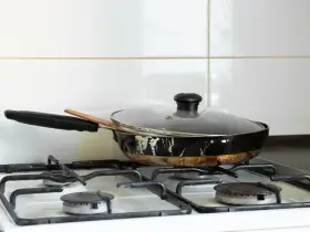 Stara, zniszczona patelnia na kuchence gazowej. Zastanawiasz się, gdzie wyrzucić patelnię?