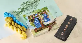 Agujas para bordar en bastidor, hilos de colores y un estuche con la palabra "PUNCH".