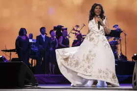 Aretha Franklin w białej sukni z haftem, śpiewa na scenie z chórem. Jej dzieci z pewnością byłyby dumne.