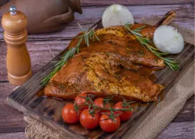 Carne marinada, lista para cocinar. El secreto ibérico se revela con romero, tomates y cebolla.