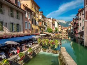 Canal animé à Annecy, avec des restaurants en terrasse et des fleurs colorées. Idéal pour découvrir les choses à faire à Annecy.