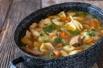 Gorąca zupa z makaronem, kawałkami kurczaka i marchewką, posypana natką pietruszki. Czy zupa to obiad? Zdecydowanie tak!