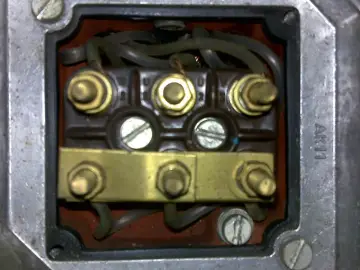 Terminal box of a three-phase motor with wires and brass connectors.