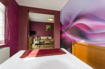 Pokój w hotelu Apollo Darłówko z kolorową tapetą i wygodnym łóżkiem.