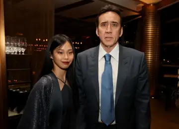 Nicolas Cage w garniturze i jego żona w ciemnej sukience i błyszczącym narzutce.