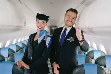 Uśmiechnięci steward i stewardessa LOT w uniformach, gotowi do lotu. Marzysz, jak zostać stewardessą? To może być Twój początek!