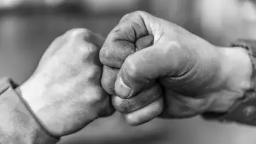 Zwei Fäuste stoßen zusammen, ein Zeichen von Solidarität und Verbundenheit.