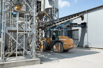 Ładowarka pracuje przy betonarni, gdzie można dowiedzieć się, jak obliczyć kubik betonu.