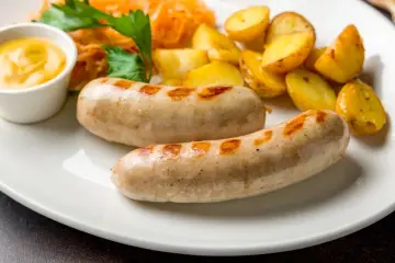 Dwie białe kiełbaski z grilla, ziemniaczki, surówka i musztarda. Idealne danie, gdy zastanawiasz się, co zrobić z białej kiełbasy.