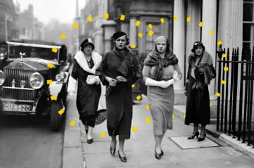 Vier Frauen in eleganter 30er Jahre Mode, Pelzmänteln und Hüten spazieren an einem Oldtimer entlang.