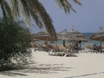 Plaża na Djerbie z leżakami i parasolami. Ludzie odpoczywają, co sugeruje, że na Djerbie jest bezpiecznie.