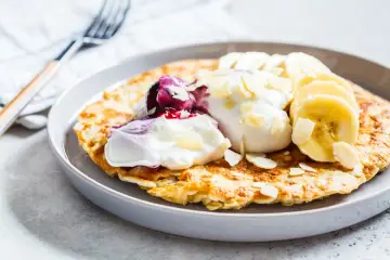 Puszysty omlet z bananem, jogurtem, musem jagodowym i płatkami migdałów. Idealne śniadanie.