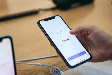 Dłoń trzyma smartfon, na ekranie którego wyświetla się komunikat "Face ID". Wygląda na to, że Face ID nie działa.