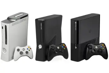 Trzy konsole Xbox 360 w różnych kolorach i wersjach, z kontrolerami. Pamiętasz, kiedy wyszedł Xbox 360?