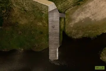 Drewniany pomost nad rzeką, z dwoma osobami, to jedna z atrakcji Nowego Korczyna.